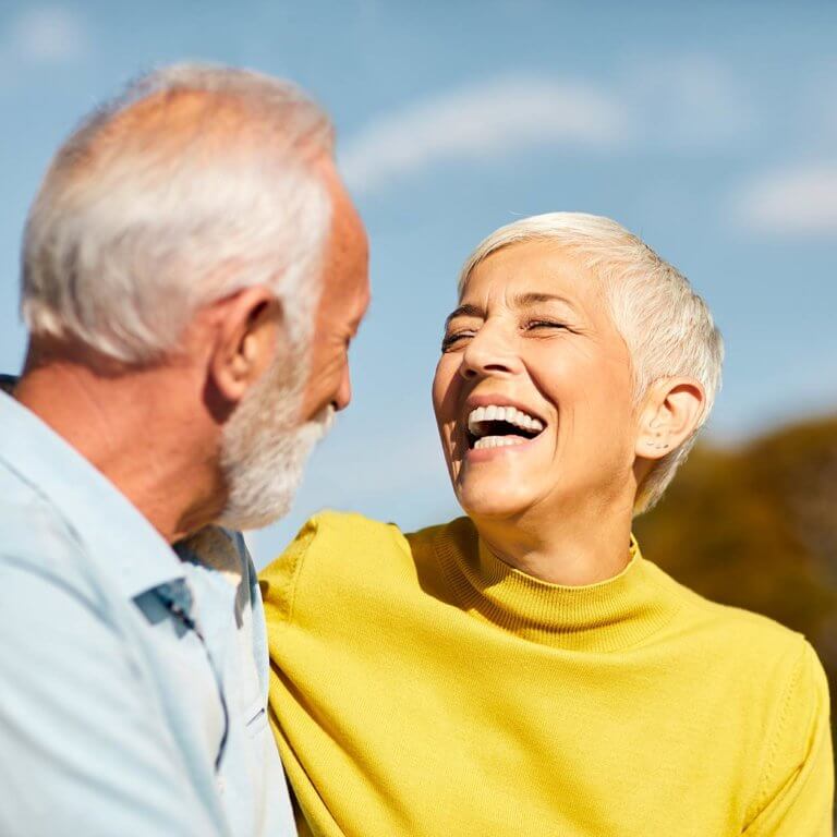 elderly couple laughing and enjoying their great teeth