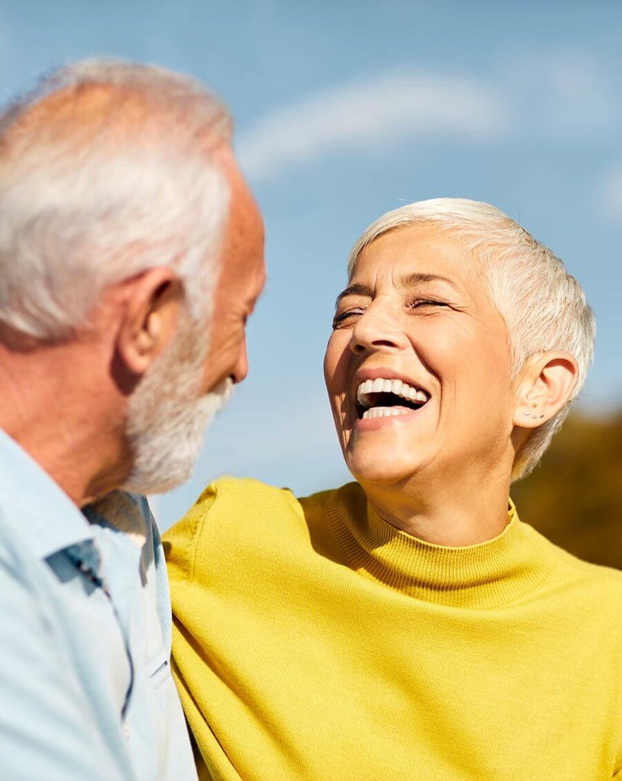 elderly couple laughing and enjoying their great teeth